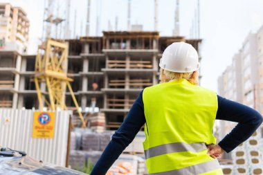 İnşaat alanında çalışan bir kadın müteahhit süreci kontrol ediyor..