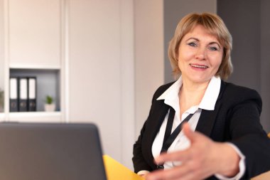 Beyaz gömlekli bir kadın iş odasında dinleyicilere koçluk yapıyor..