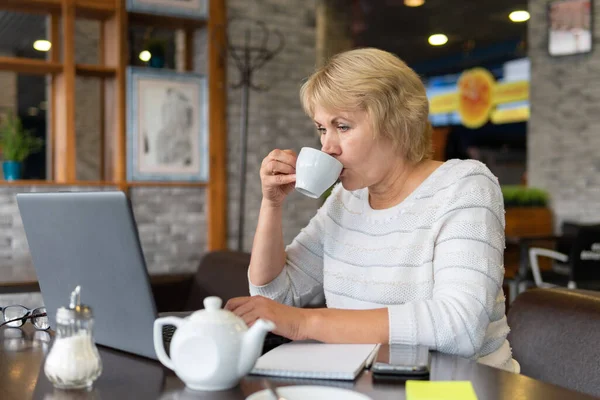 Una Mujer Trabaja Una Laptop Café Mujer Mediana Edad Bebiendo — Foto de Stock