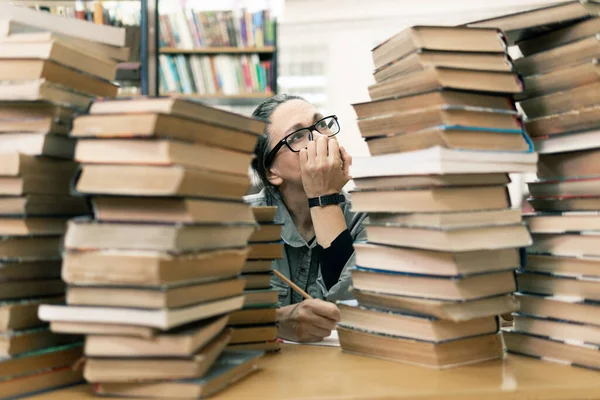 Kütüphanede kitap arayan bir kadın. Orta yaşlı bir kadın kitaplıktaki bir kitaba bakıyor. Yeni yön ve yöntemler öğreniyor..