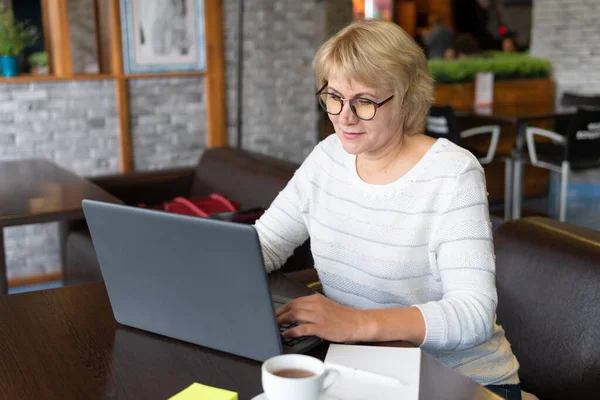 Kvinna Jobbar Laptop Ett Kafé Medelålders Kvinna Dricker Och Tittar — Stockfoto