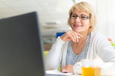 Bir kafede dizüstü bilgisayarda çalışan bir kadın. Orta yaşlı kadın çay içiyor ve haberleri izliyor. O bir serbest çalışan..