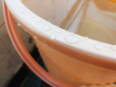 Bir kovaya su damlalarını yakın çekim, seçici odaklanma.