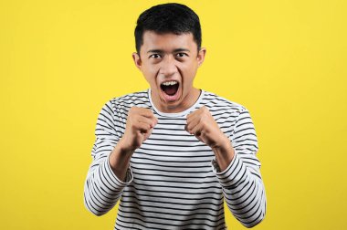 Asyalı genç adam kızgın, sinirli ve duygusal hareketler yapıyor.