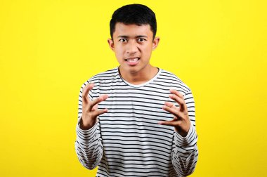 Asyalı genç adam kızgın, sinirli ve duygusal hareketler yapıyor.