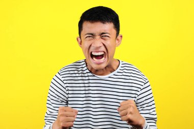 Asyalı genç adam kızgın, sinirli ve duygusal hareketler yapıyor.