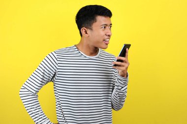 Genç Asyalı adam ekrandaki telefonun önünde sinirli sinirli konuşuyor.