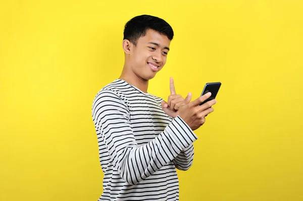 快乐的年轻英俊的亚洲男人用智能手机微笑 — 图库照片