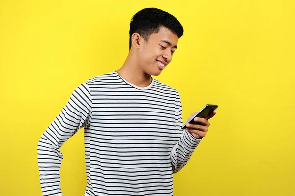 Akıllı telefon kullanarak gülümseyen yakışıklı Asyalı genç adam.