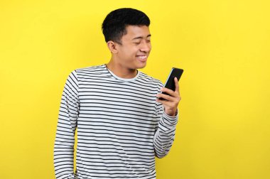 Akıllı telefon kullanarak gülümseyen yakışıklı Asyalı genç adam.