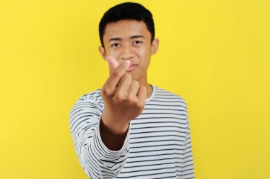 Mutlu Asyalı genç adam parmak kalbi yapıyor. Aşkın işareti, aşkın sembolü.