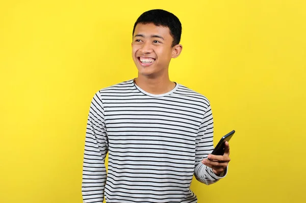 Glad ung snygg asiatisk man ler med smartphone — Stockfoto