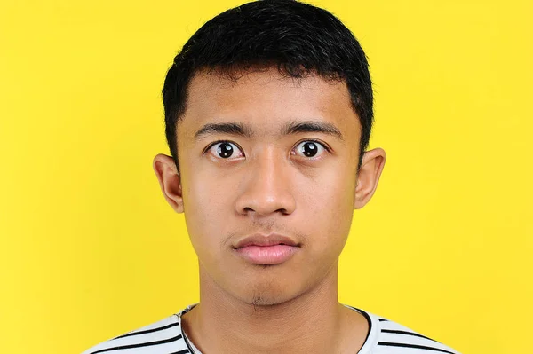 Very serious young Asian man looking at camera isolated on yellow — Stock Photo, Image