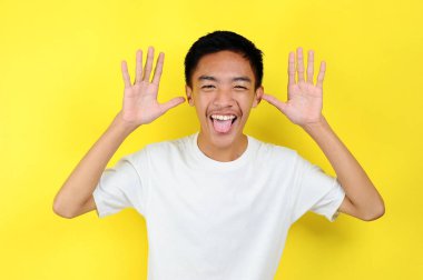 Komik Asyalı genç adam bağırıyor. Tuhaf görünüyor, sarı renkte izole edilmiş.