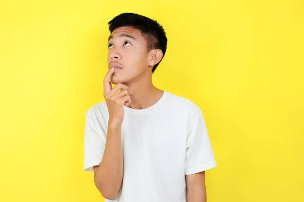 Portrait of smart young Asian man thinking and look up. Smart young Asian man wearing white t-shirt thinking and look up