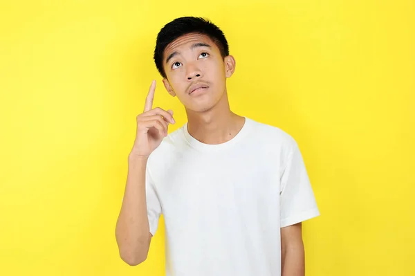 Porträtt av en smart ung asiatisk man som tänker och tittar upp. Smart ung asiatisk man bär vit t-shirt tänkande och titta upp — Stockfoto