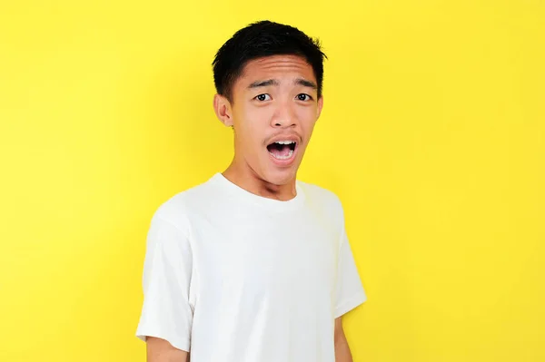 Shocked face of Asian man in white shirt on yellow — Stock Photo, Image