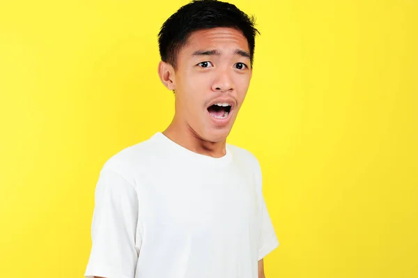 Шокированное лицо азиата в белой рубашке на желтом — стоковое фото