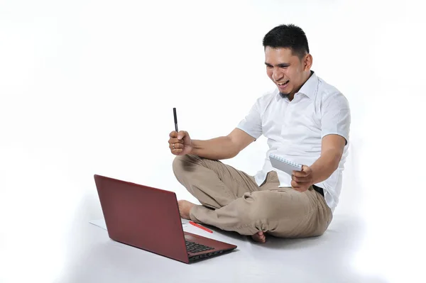 Νεαρός Ασιάτης επιχειρηματίας ή Νεαρός Ασιάτης επιχειρηματίας κάθεται στο λευκό πάτωμα κρατώντας φορητό υπολογιστή. Ενθουσιασμένος από τους νέους ελεύθερους επαγγελματίες της Ασίας. — Φωτογραφία Αρχείου