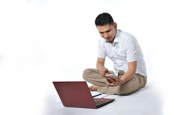 Retrato de empresário asiático sentado no chão branco e chamando o telefone apontado para a tela do telefone — Fotografia de Stock