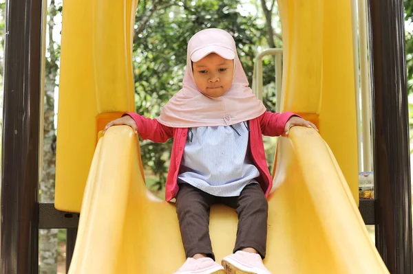 Gadis kecil yang lucu bermain di slide di luar ruangan. Gadis manis bermain slide pada akhir pekan — Stok Foto