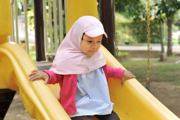 Pequena menina bonito jogando no slide ao ar livre. Menina bonito jogar no slide no fim de semana — Fotografia de Stock