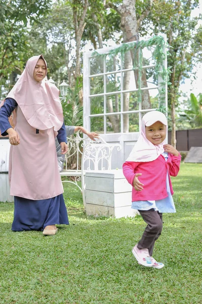 Glücklich junge asiatische Mutter spielt mit ihrer Tochter im Hinterhof. — Stockfoto