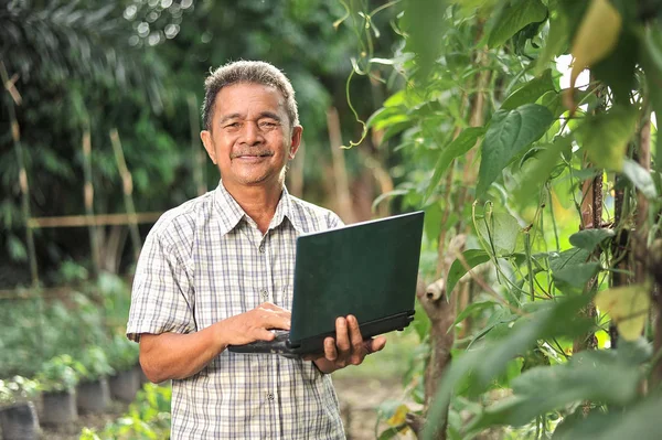 Üst düzey Asyalı çiftçinin dizüstü bilgisayarı olmasından mutlu.