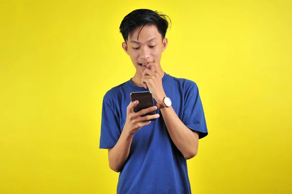 Bahagia pemuda tampan Asia tersenyum menggunakan smartphone — Stok Foto
