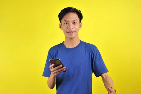 Blij van jong goed uitziende Aziatische man glimlachen met behulp van smartphone — Stockfoto