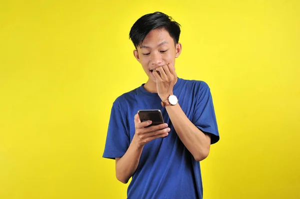 Geschokt gezicht van Aziatische man in wit shirt op zoek naar telefoon scherm — Stockfoto