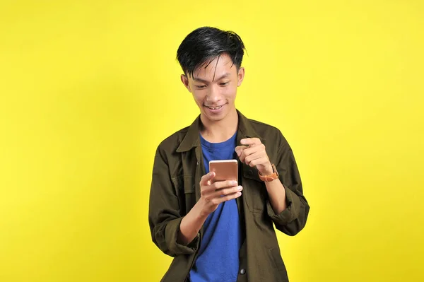 Blij van jong goed uitziende Aziatische man glimlachen met behulp van smartphon — Stockfoto