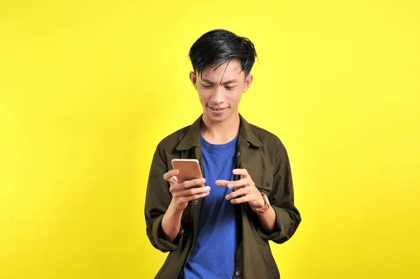 很高兴年轻英俊的亚洲男人用智能手机微笑 — 图库照片
