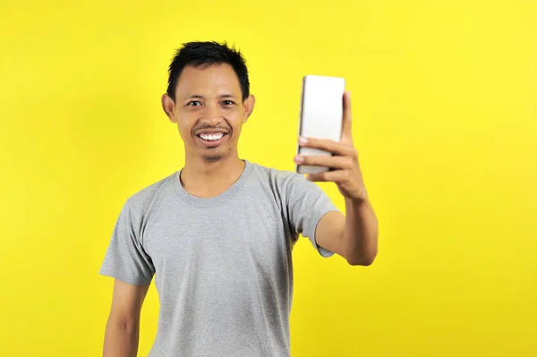 Portrait of cool cheerful Asian man having video-call with lover — 스톡 사진