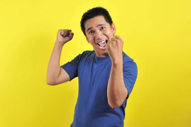 Asyalı genç adam mutlu ve heyecanlı kazanan jestler yapıyor. Başarılı ve kutlayıcı.