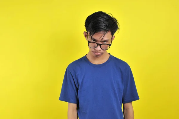 Відчуваючи нудьгу, молодий азіат у окулярах ізольований від жовтого. — стокове фото