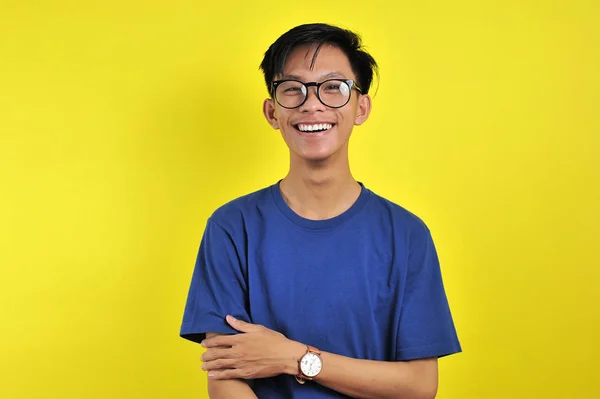 Щасливий чоловік з Азії посміхається в окулярах, ізольованих на жовтому — стокове фото