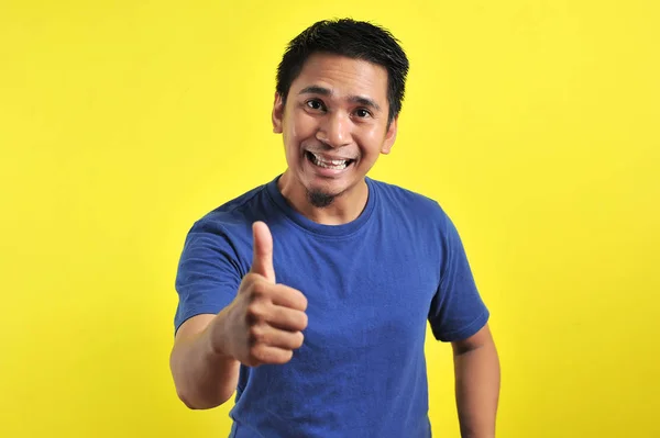 Portret młodego Azjaty śmiejącego się z podniesionymi kciukami przed kamerą — Zdjęcie stockowe