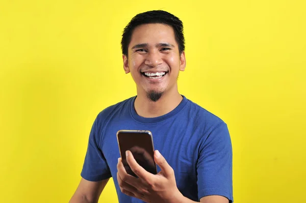 Happy young good looking Asian man smiling using cellphone — 스톡 사진