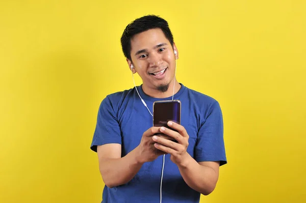 Asian man in casual blue t-shirt wearing headset listening music — 스톡 사진