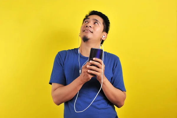 Азіатський чоловік у блакитній футболці з навушниками, що слухають музику — стокове фото