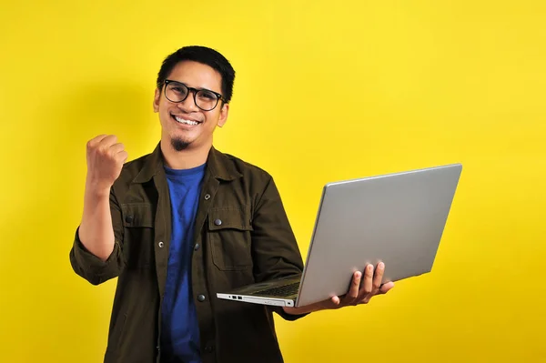 Asian man holding laptop with winning gesture, winning gift or lottery