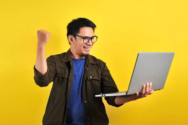 Asiático homem segurando laptop com gesto vencedor, ganhando presente ou loteria — Fotografia de Stock