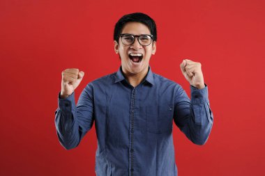 Genç Asyalı adam mutlu ve heyecanlı bir şekilde galibiyet jesti yaptı. Su