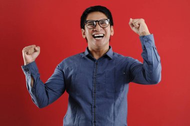 Genç Asyalı adam mutlu ve heyecanlı bir şekilde galibiyet jesti yaptı. Su