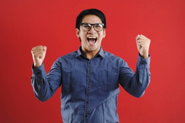 Genç Asyalı adam mutlu ve heyecanlı bir şekilde galibiyet jesti yaptı. Su