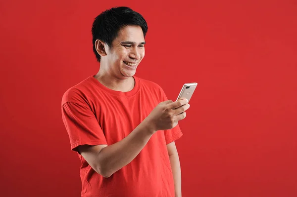 快乐的亚洲人在手机上阅读新的文字 在红色背景下被隔离 — 图库照片