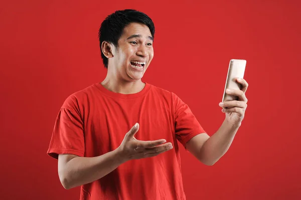 快乐的亚洲人在手机上阅读新的文字 在红色背景下被隔离 — 图库照片