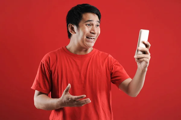 Glad Asiatisk Man Läser Text Mobilen Isolerad Röd Bakgrund — Stockfoto