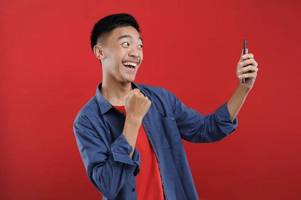스마트폰을 휴대폰을 아시아 청소년 해피는 배경에 고립된 온라인에서 선물을 받는다 — 스톡 사진
